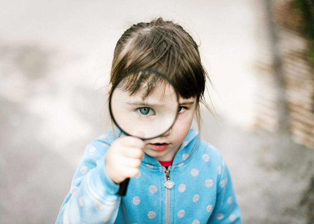 child-w-magnifying-glass child looking through magnifying glass