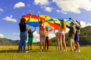 kids lifting up rainbow tarp